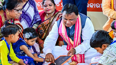 CM Mohan Charan Majhi helping a child write ‘sunya’ (zero) on a slate during the ‘Khadi Chuaan’ ritual on Wednesday.