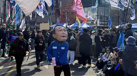 A man wearing a mask of President Yoon Suk Yeol celebrates along with others after Yoon was removed from office, near royal palace in downtown Seoul, South Korea, Friday, April 4, 2025.