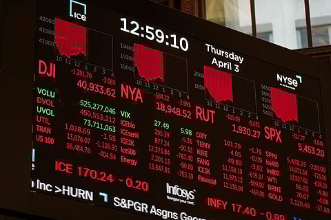 A screen displays financial news as traders work on the floor at the New York Stock Exchange in New York, Thursday, April 3, 2025.