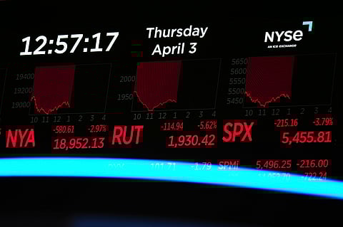A screen displays financial news as traders work on the floor at the New York Stock Exchange in New York, Thursday, April 3, 2025.