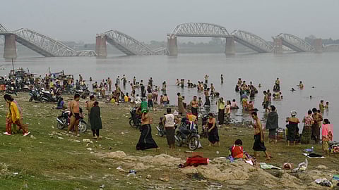 People bathe in the Irrawaddy River in front of the collapsed Ava Bridge, also known as the Inwa Bridge, in Sagaing on April 2, 2025, as residential areas remain without electricity or running water five days after a major earthquake struck central Myanmar.