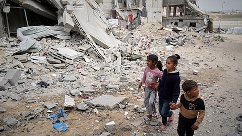 Children walk by the destroyed house of journalist Islam Meqdad, where she was killed along with her son and five other family members in an Israeli army strike in Khan Younis, southern Gaza Strip, Sunday, April 6, 2025.