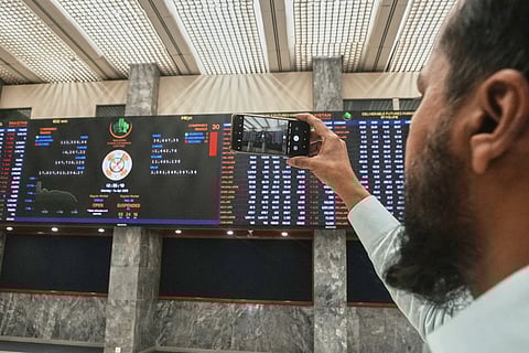 An investor takes a picture with cellphone of indexes and benchmark 100 index at the Pakistan stock exchange in Karachi