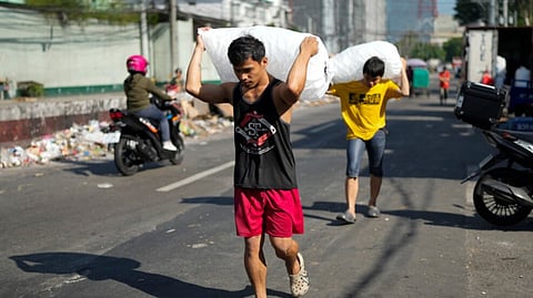 Men deliver sacks of ice cubes as demand remains high due to hot temperatures in Quezon city, Philippines.