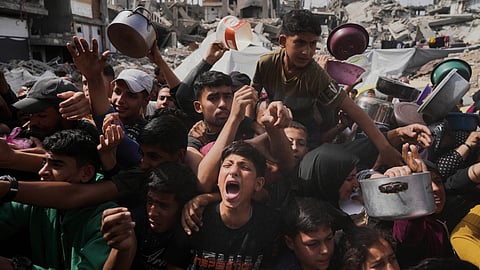 Palestinians wait to get donated food at a distribution center in Beit Lahiya in the northern Gaza Strip, Monday, April 7, 2025.
