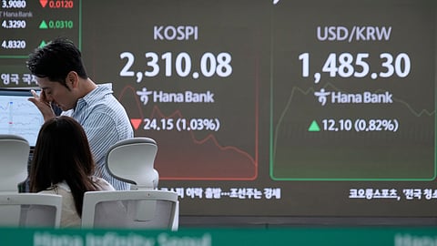 A currency trader reacts near a screen showing the Korea Composite Stock Price Index (KOSPI), and the foreign exchange rate between U.S. dollar and South Korean won, right, at the foreign exchange dealing room of the KEB Hana Bank headquarters in Seoul, South Korea, Wednesday, April 9, 2025.