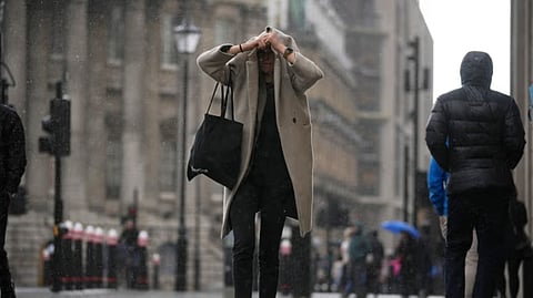A woman walks past the Bank of England, at the financial district, in London, Thursday, March 13, 2025.