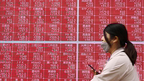A person walks past an electronic stock board at a securities firm in Tokyo Thursday, April 10, 2025.