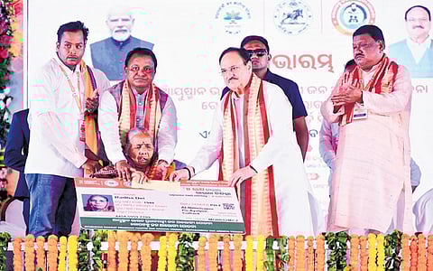 Union Minister JP Nadda and CM Mohan Charan Majhi handing over co-branded AVVY card to an elderly beneficiary Radha Dei in Cuttack on Friday