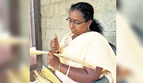 Priya Mol S inscribing Malayalam alphabets on a palm leaf