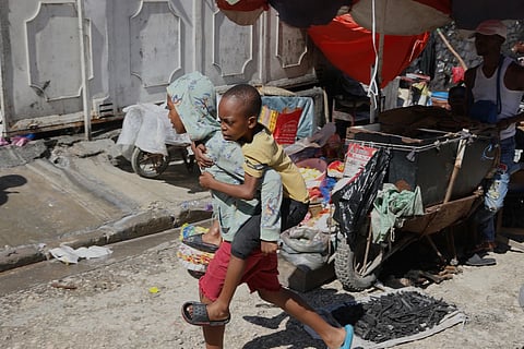 A youth carries a little boy on his back at a school that is now operating as a shelter for those fleeing their homes to escape gang violence in Port-au-Prince, Haiti, Monday, April 14, 2025.