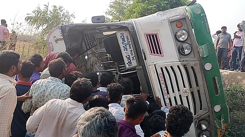 People gather near an RTC bus belonging to the Kodad depot which overturned on the outskirts of Chinthalapalem in Suryapet district on Sunday.