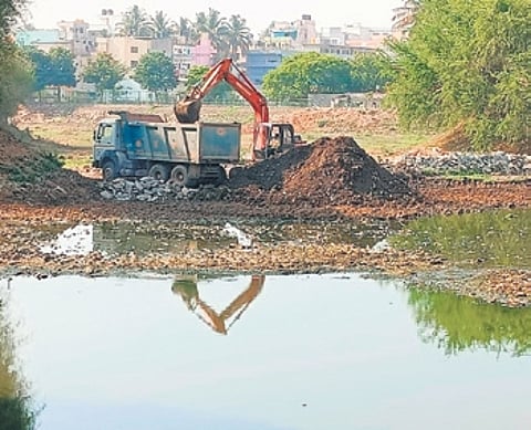 An excavator at work removing silt and muck from the lake
