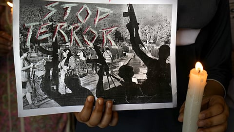 A student holds a candle and a poster in tribute to the terror attack victims of Jammu and Kashmir's Pahalgam, Wednesday, April 23, 2025.