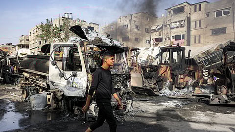 A man walks past destroyed vehicles and smouldering excavator bulldozers at the Jabalia municipality garage, which was hit by Israeli bombardment, in Jabalia in the northern Gaza Strip on April 22, 2025.