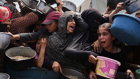 Palestinian children receive donated food at a distribution center in Khan Younis, Gaza Strip, Monday, April 21, 2025.