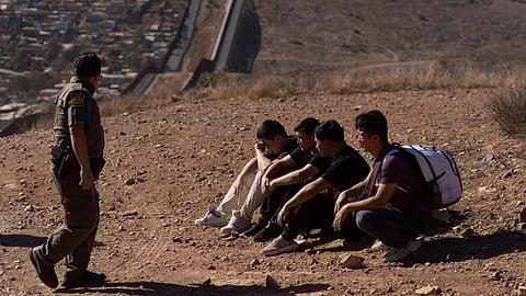 A US Border Patrol agent walks past four men being detained after crossing the border through a gap in the walls separating Mexico and the United States, Jan. 23, 2025, in San Diego.