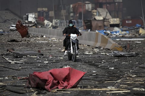 In this photo provided by Islamic Republic News Agency, IRNA, two men on a motorcycle drive through debris after a massive explosion rocked a port near the southern port city of Bandar Abbas, Iran, Saturday, April 26, 2025.