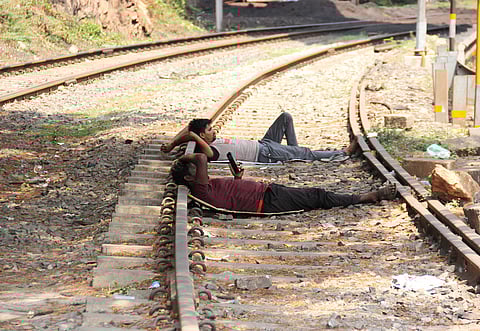 Amidst rising summer heat, workers are seen resting along railway tracks under a tree's shade near the port area in Visakhaptanam.