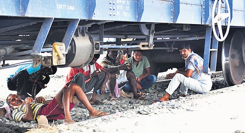 Railway labourers are seen resting beneath a goods train to shield themselves from scorching summer heat in Karimnagar