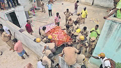 Forest department officers, along with fire and rescue services personnel and local police, capture the bear in a cage.
