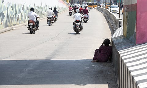 A homeless woman taking respite in a small patch of shade at a subway in Tiruchy