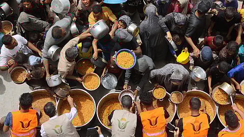 Palestinians queue for a hot meal at a charity kitchen in Gaza City on April 30, 2025