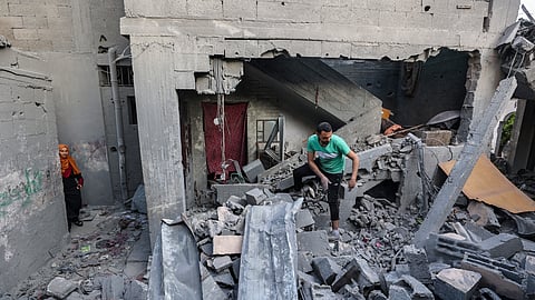 A woman looks on as a man inspects the damage on the rubble of a building hit in an Israeli strike in the Bureij camp for Palestinian refugees in the central Gaza Strip on May 2, 2025.