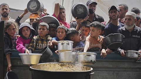 Palestinians wait to get food at a community kitchen in Khan Younis, in southern Gaza Strip, Thursday April 24, 2025.