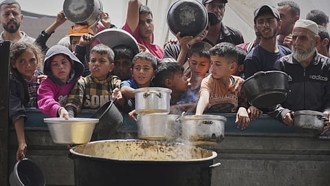 Palestinians wait to get food at a community kitchen in Khan Younis, in southern Gaza Strip.