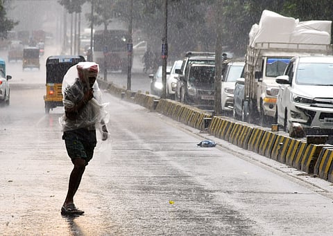 A man covers himself with a plastic sheet to protect himself from rain in Secunderabad on Friday