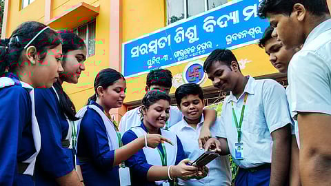 Students checking their matric exam results on mobile at Unit 3 Saraswati Sisu Vidya Mandir in Bhubaneswar on Friday.
