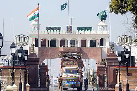 Indian and Pakistani national flags flutter as Indian Border Security Force (BSF) personnel (L) and Pakistani Rangers (R) allow a Pakistani truck to cross over to India at the Wagah Border