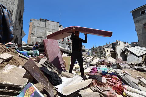 A Palestinian clears debris following overnight Israeli strikes, at the Nuseirat refugee camp in the central Gaza Strip on May 4, 2025.