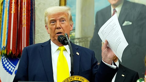 President Donald Trump holds a document with notes about Kilmar Abrego Garcia as he speaks with reporters in the Oval Office of the White House, April 18, 2025, in Washington.
