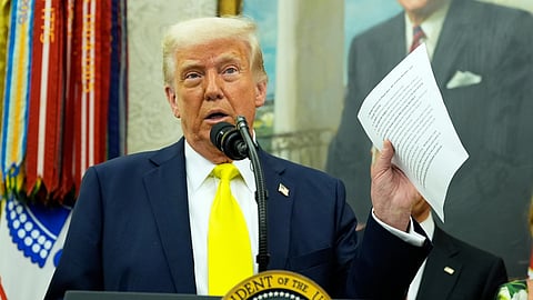 President Donald Trump holds a document with notes about Kilmar Abrego Garcia as he speaks with reporters in the Oval Office of the White House, April 18, 2025, in Washington.