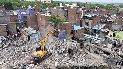 A backhoe loader being used to demolish illegal structures during a demolition drive by the DDA, in the Taimur Nagar area of Delhi on Monday, May 5, 2025.