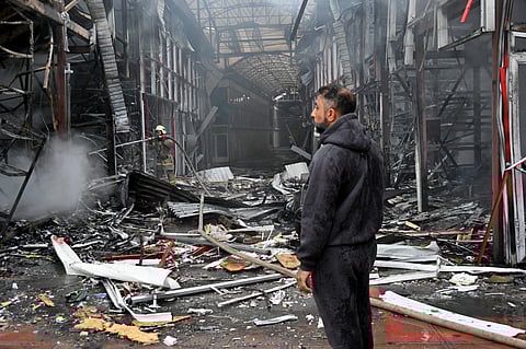 A man stands as a Ukrainian fireman finishes to put out a fire at the "Barabashovo" market following a drone strike in Kharkiv on May 6, 2025 amid the Russian invasion of Ukraine.