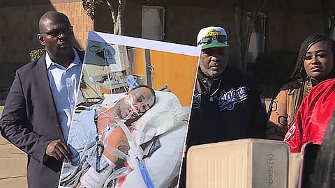 In this photo provided by WREG, Tyre Nichols' stepfather Rodney Wells, center, stands next to a photo of Nichols in the hospital after his arrest, during a protest in Memphis, Tenn., Jan. 14, 2023.