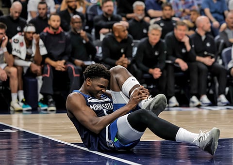 Minnesota Timberwolves guard Anthony Edwards (5) grabs his leg on the court during the first half of Game 2 of an NBA basketball second-round playoff series against the Golden State Warriors, Thursday, May 8, 2025, in Minneapolis.
