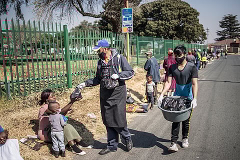Volunteers for the grassroots charity Hunger has no Religion distribute food parcels to women queueing during a special lunch services.