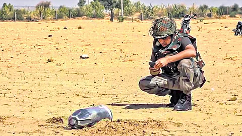 A security personnel inspects the debris of an unidentified projectile which landed amid the military conflict between India and Pakistan, in Jaisalmer, Rajasthan, Saturday.