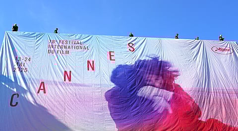 Workers hang the official poster of the 78th Cannes Film Festival on the facade of the Palais des Festivals in Cannes, south-eastern France, on May 11, 2025.
