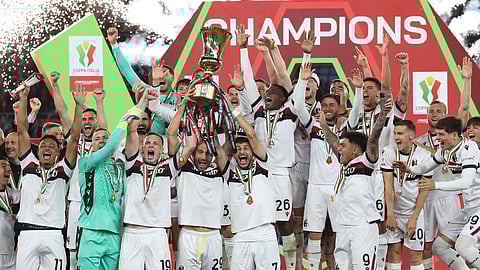 Lewis Ferguson, Lorenzo De Silvestri and Riccardo Orsolini of Bologna lift the Coppa Italia trophy as their teammates celebrate after the team’s victory in the Coppa Italia final against AC Milan.
