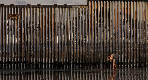 A man takes an image with his phone next to where the border wall separating Mexico and the United States reaches the Pacific Ocean Tuesday, Jan. 28, 2025, in Tijuana, Mexico.
