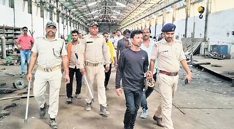 Police taking the accused for crime scene recreation on the factory premises