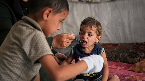 A little boy is fed by his mother with food from a community kitchen at the Muwasi camp for displaced Palestinians in Khan Younis, southern Gaza Strip, Sunday, May 18, 2025.
