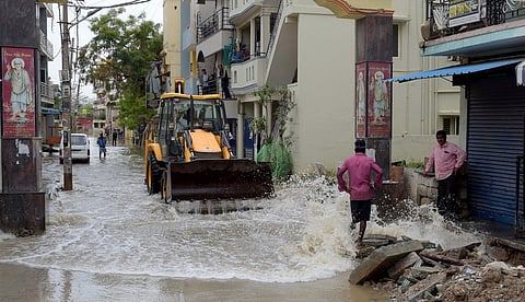 BBMP workers clearing the rain water logged on the roads at Sai Layout in Bengaluru