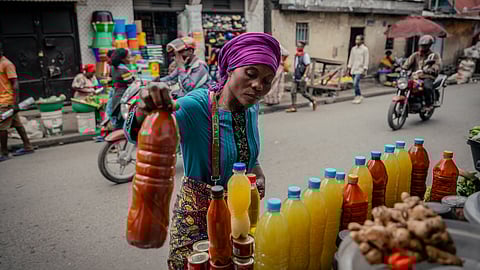 A vendor sells bottles of palm oil measured in koroboyi, a local unit, along with tomatoes and other food products at Birere Market in Goma on May 15, 2025.