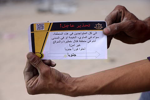 A Palestinian man holds a leaflet dropped by the Israeli army, warning people in Jabalia in the Northern Gaza Strip to flee toward the southern part of the territory, on May 22, 2025. The Israeli army issued an evacuation warning on May 22 for 14 neighbourhoods of northern Gaza, as it pressed a renewed offensive that has drawn international condemnation.